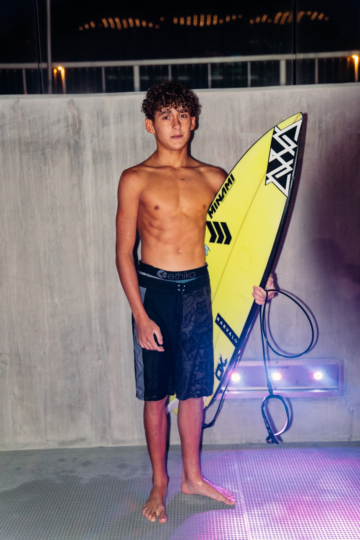 AVVA grom holding a yellow shortboard