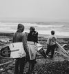 AVVA team riders on the beach holding their surf boards viewing the waves.