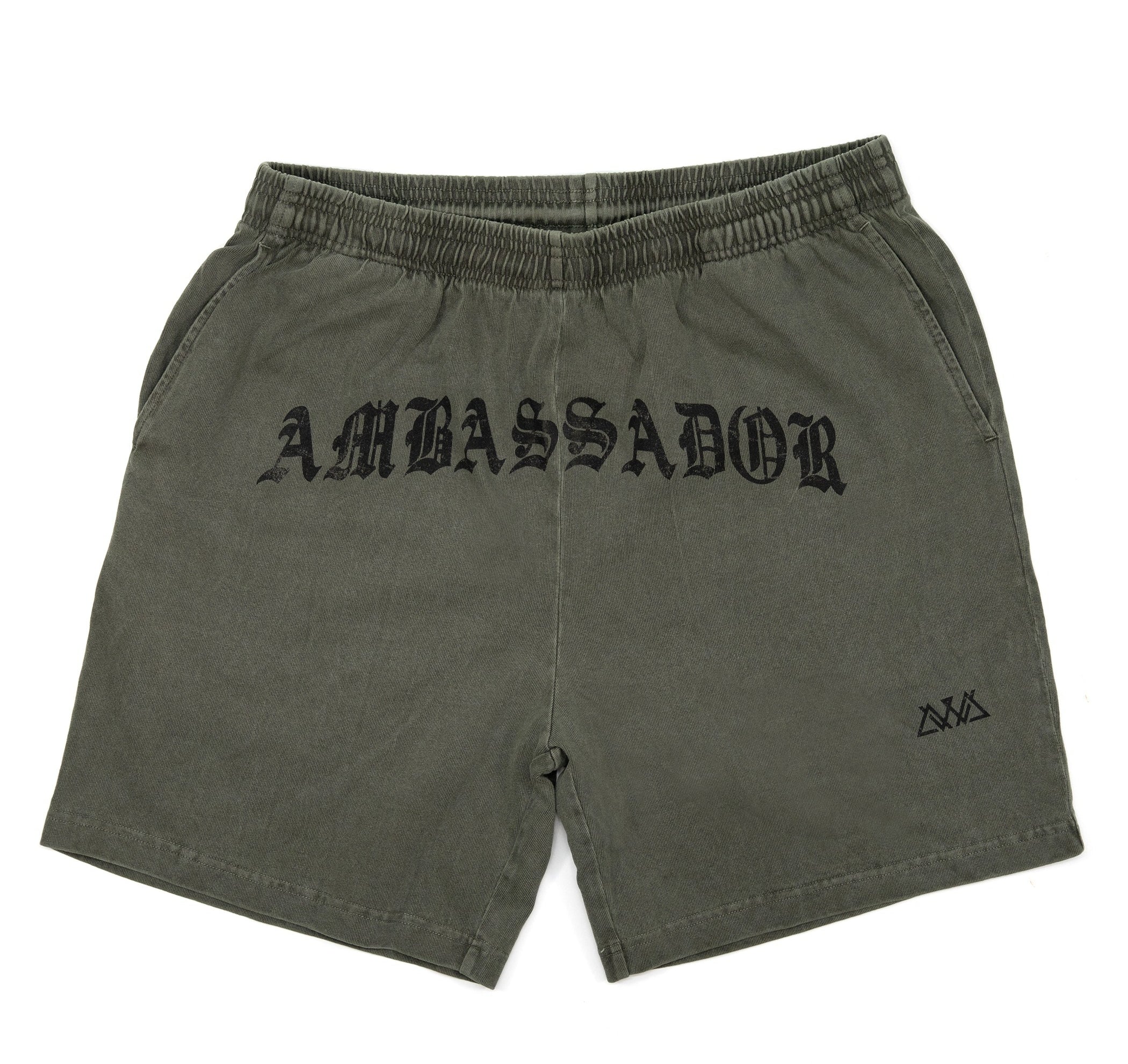 FRONT VIEW OF KHAKI PIGMENT DYED HILO SHORT WITH LARGE AMBASSADOR LOGO IN THE MIDDLE IN OLD ENGLISH WRITING WITH SMALL AVVA LOGO ON LEFT LEG. 