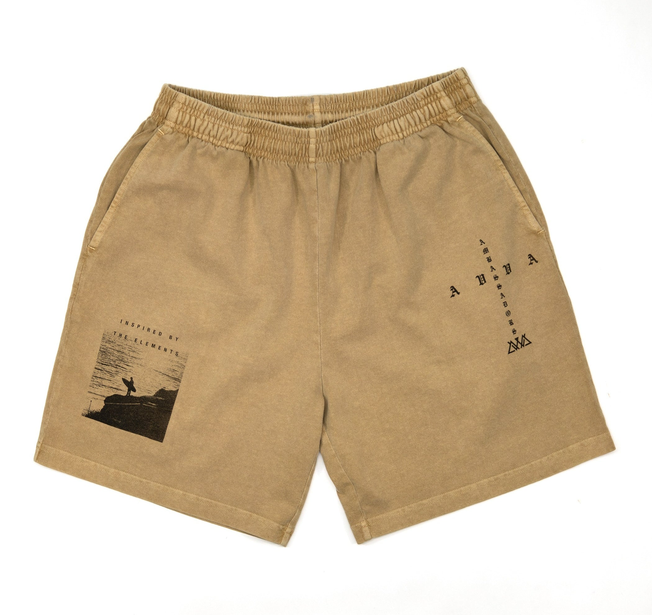 FRONT VIEW OF KHAKI PIGMENT DYED HILO SHORT. SHOWING CROSS SHAPED LOGO ON LEFT LEG AND INSPIRED BY THE ELEMENTS LOGO AND PICTURE OF SURFER HOLDING BOARD LOOKING AT WATER ON RIGHT SIDE LEG.
