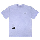 FRONT VIEW OF PURPLE ISLAND HAZE TEE.  SMALL AVVA LOGO IN TOP RIGHT CORNER WITH A INSPIRED BY THE ELEMENTS GRAPHIC OF SURFER HOLDING SURFBOARD LOOKING AT THE WATER IN BOTTOM LEFT CORNER.