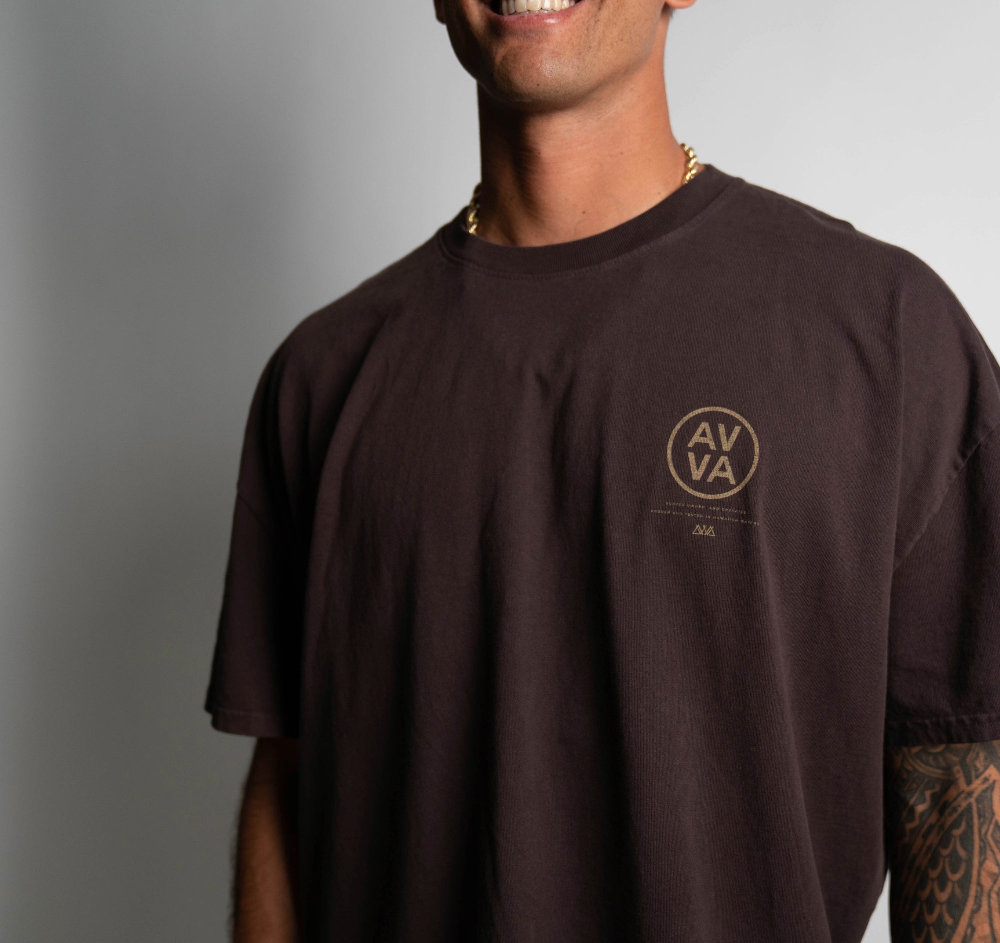 FRONT VIEW OF BROWN HEAVYWEIGHT CREED TEE ON MODEL LOOKING FORWARD. HIGHLIGHTING TOP RIGHT AVVA LOGO.
