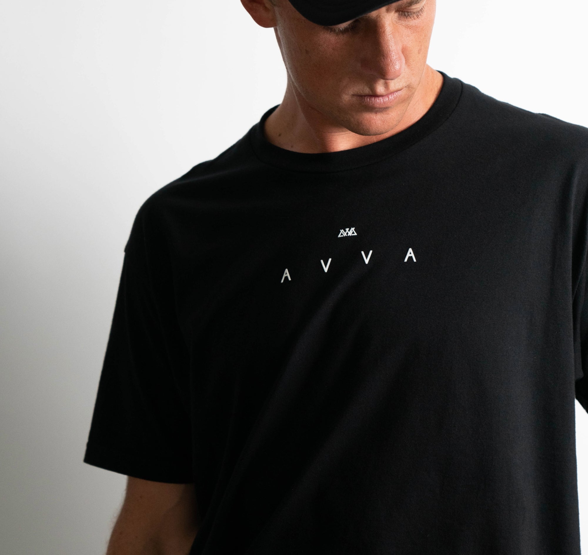 FRONT VIEW OF ELEMENTS TEE. MODEL WEARING IT LOOKING TO THE LEFT. HIGHLIGHTS THE SIMPLE AVVA LOGO ON FRONT CENTER MIDDLE CHEST OF THE TEE.
