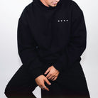 FRONT VIEW OF MODEL WEARING THE AVVA VELOCITY FLEECE HOODIE HIGHLIGHTING THE CORNER AVVA LOGO