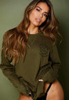 FEMALE MODEL WEARING ALL NATIONS REVERSIBLE CREW ON MODEL. FRONT VIEW, MILITARY GREEN.