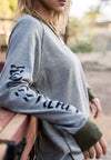 FEMALE MODEL WEARING ALL NATIONS REVERSIBLE CREW ON MODEL. CLOSE UP OF SLEEVE AND TORSO. 
