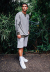 MODEL IN JUNGLE WEARING ALL NATIONS REVERSIBLE CREW ON MODEL. SHOWING THE INSIDE OF THE SWEATSHIRT, PALE GREEN.