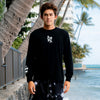 FRONT VIEW OF MODEL WEARING KAILUA BLACK LONG SLEEVE TEE IN FRONT OF THE BEACH