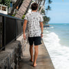 BACK VIEW OF MODEL WALKING AWAY ALONG WALKWAY NEXT TO THE BEACH WEARING KAPALUA TEE
