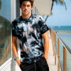FRONT VIEW OF MODEL WEARING KUHIO CRYSTAL CUSTOME DYED TEE WITH THE BEACH IN THE BACKGROUND