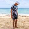 QUARTER VIEW OF MODEL ON BEACH WEARING KUHIO CRYSTAL CUSTOME DYED TEE