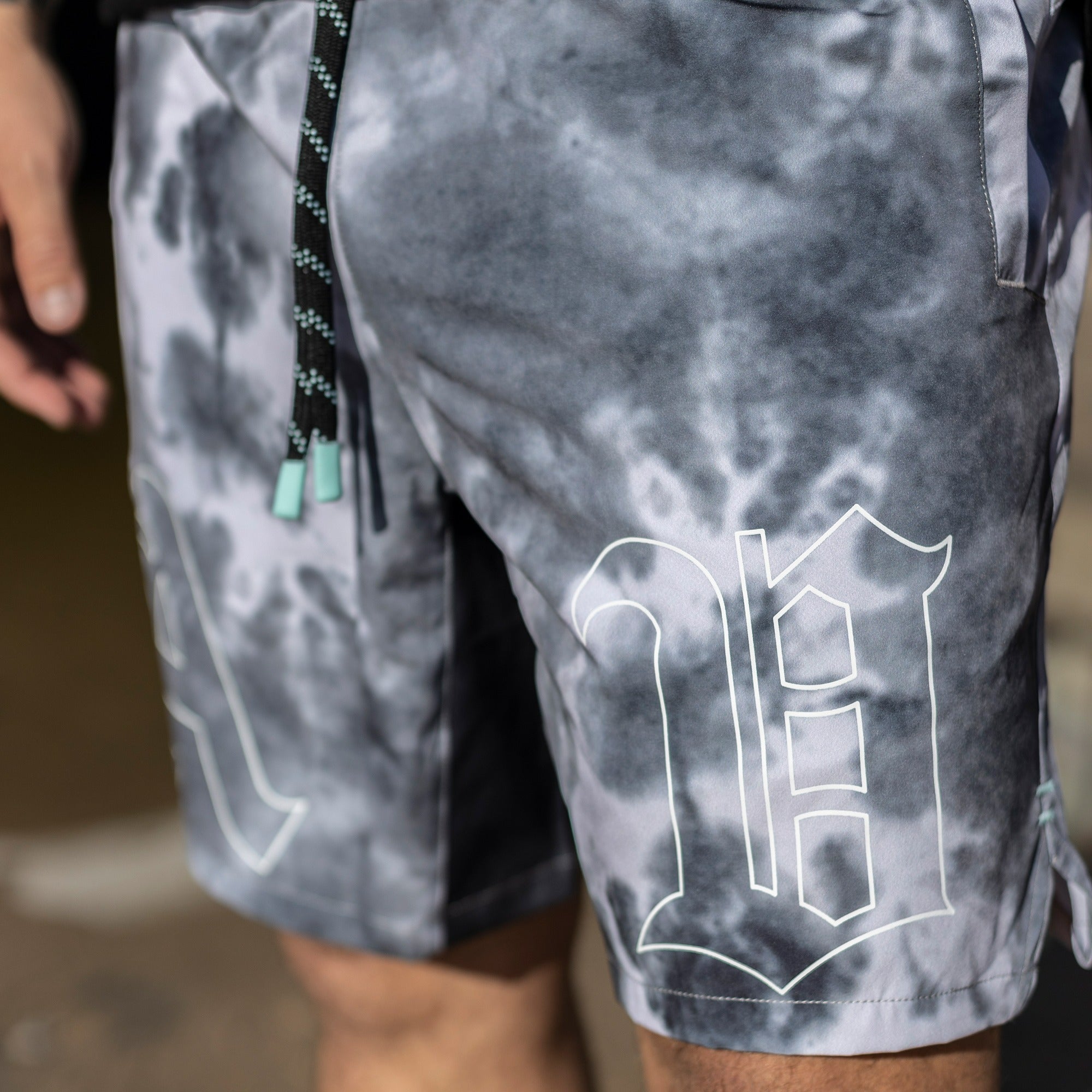 EXTREME FRONT CLOSE UP OF DETAIL PRINT OF SMOKE WATER CLOUD WASH TRAINING SHORTS WORN BY MODEL KEKOA.