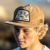 FRONT VIEW OF MODEL WEARING KONA KONA KHAKI CORDUROY HAT. FRONT WOVEN PATCH WITH CUSTOM LOGO EMBROIDERY AND SIDE LOGO EMBROIDERY.