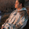 MODEL KEKOA WEARING KAVA KELP HOODIE SITTING ON BENCH LOOKING OUT INTO THE SUNSET.