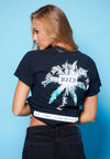 BACK VIEW OF FEMALE MODEL WEARING BLOOD PALMS BLACK TEE IN STUDIO WITH BLUE BACK DROP