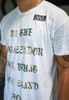 CLOSE UP OF MODEL WEARING BE THE AMBASSADOR WHITE TEE.SCREEN PRINT IN CAMO COLORING.