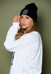 FRONT SIDE VIEW OF MODEL WEARING THE BERLIN BLACK BEANIE WITH OLIVE BACKGROUND
