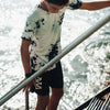 MODEL LOOKING DOWN AT STAIRS WEARING BLACK SAND BOARDSHORT AND PHEAHI BOMBS TEE AT THE BEACH.