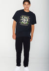 FRONT VIEW OF MODEL WEARING COAST TO COAST BLACK TEE. CAMO PRINT DETAIL WITH AVVA LOGO. WE ARE THE AMBASSADORS. IN STUDIO.
