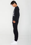 SIDE VIEW OF MODEL LOOKING DOWN WEARING CHAZ MOSAIC WEARING BLACK LONG SLEEVE TEE IN STUDIO