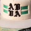 EXTREME FRONT CLOSE UP OF FRONT OF CHESTER WHITE HAT. 3D AVVA LOGO EMBROIDERY DETAIL WITH EMBROIDERED BAR DETAILS.