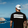 BACK VIEW OF MODEL WEARING CHESTER BLACK TEE LOOKING OUT TO THEOCEAN
