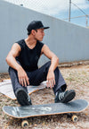 SIDE VIEW OF MODELS HEAD WEARING ELE 7 PANEL BLACK HAT SITTING ON GROUND WITH SKATE BOARD