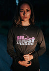 FRONT VIEW OF MODEL WEARING ILLEST AMBASSADOR BLACK LONG SLEEVE TEE AT NIGHT TIME WITH CAR HEADLIGHTS SHINGING ON HER
