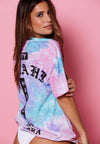 BACK VIEW OF MODEL WEARING LOKAHI CORAL WASH TEE WITH PINK BACKGROUND