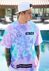 FRONT VIEW OF MODEL WEARING LOKAHI CORAL WASH TEE WITH POOL IN BACKGROUND