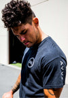 CLOSE UP SIDE VIEW OF MODEL WEARING NIXON BLACK TEE FEATURING FRONT CHEST AND SLEEVE SCREEN PRINT DETAILS