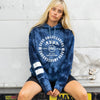FRONT VIEW OF MODEL SITTING ON THE BACK OF A BOX TRUCK WEARING PURE ALOHA HOODIE. FEATURING THE LARGE FRONT SCREEN PRINT AND SLEEVE PRINT
