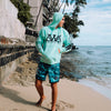 FRONT VIEW OF MODEL WEARING REPRESENT 2.0 MINT HOODIE LOOKING OUT TO THE OCEAN