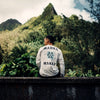 BACK VIEW OF MODEL WEARING VAST LONG SLEEVE SITTING ON LEDGE WITH LUSH GREEN JUNGLE VIEW